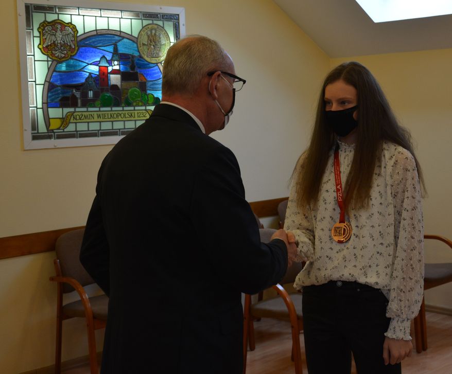 Na zdjęciu burmistrz Koźmina Wielkopolskiego gratuluje lekkoatletce.