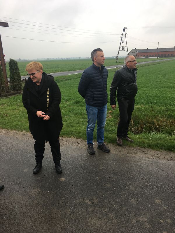 Dwóch mężczyzn i kobieta stoją przy drodze.