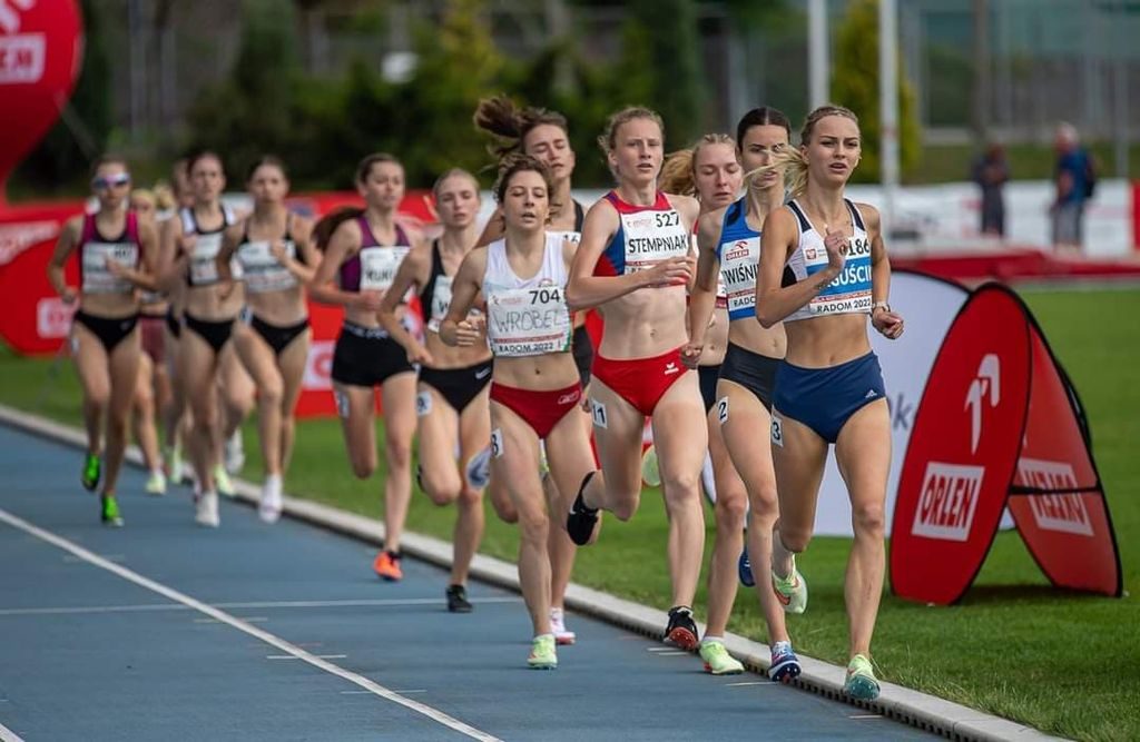 Zawodniczki biegną na stadionie.