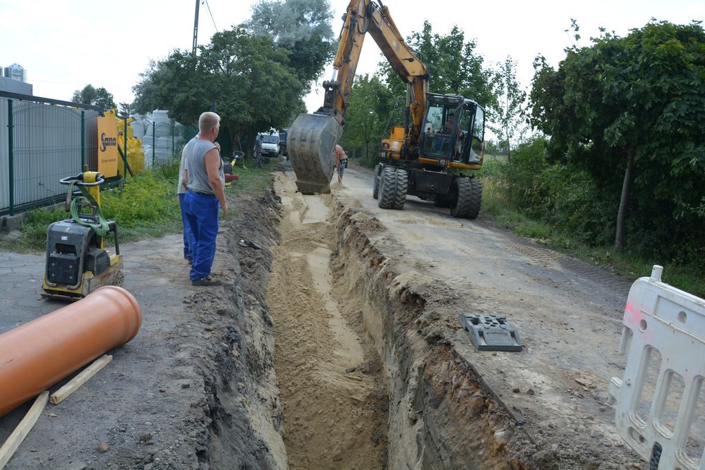 Koparka rozsypuje piasek w wykopie