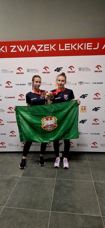 Dwie biegaczki prezentują flagę Koźmina Wielkopolskiego.