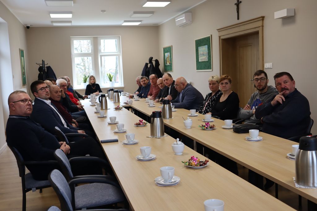 Uczestnicy spotkania siedzą przy długim stole.